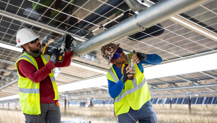 Two workers under a solar panel