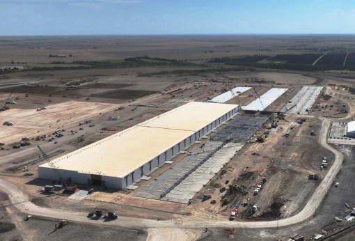 Aerial view of a large industrial data center construction site in Milam County surrounded by rural terrain and solar fields.